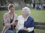 Younger and older woman on park bench with phone